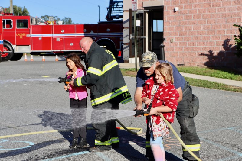 Evelina Sadkowski, left, and Adaline Dusza get to use a fire hose to put out a simulated burning house. Both girls are students at H.O. Brittingham Elementary School in Milton.