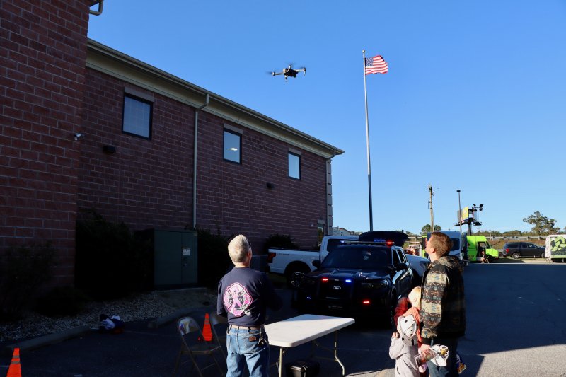 Lewes firefighter Glenn Marshall, left, demonstrates the department’s drone for Charlie and Ethan Monk, and their dad Kyle.