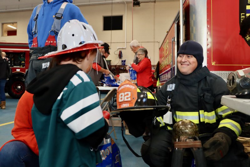 Firefighter Stephen Matthews, right, lets Hank Karsnitz of Milton try on a firefighter’s helmet.