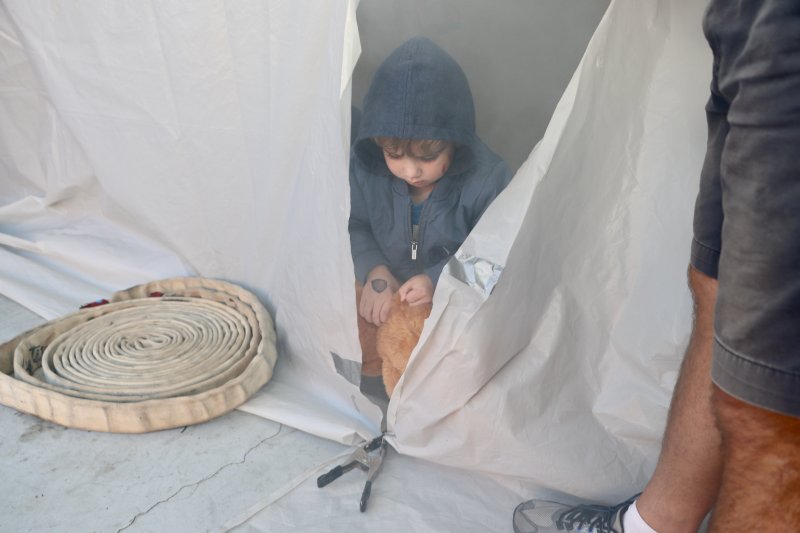 Jacob Mullins crawls out of the smoke tent with a teddy bear. The tent simulates what firefighters see when they enter a burning building and search for people who might be inside.