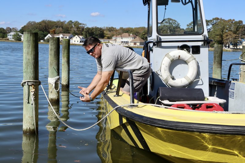Mike Rice demonstrates how he leaned over the side of the boat and grabbed on to Mike Kobach. The Sea Tow boat in the photo is smaller than the one Rice was operating, so he had to reach farther down to make the rescue. “Like a bear hug, I pulled him up,” Rice said.