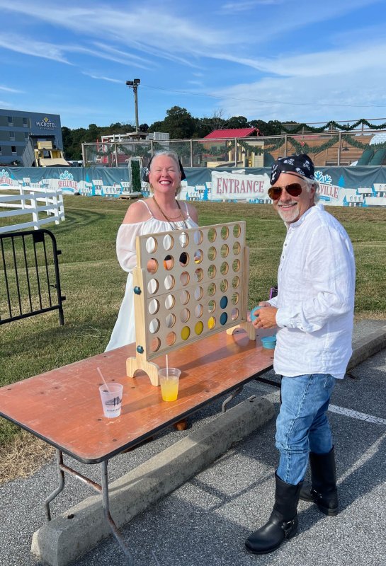 Jennie Hatton Baver, left, director of marketing and communications at La Vida Hospitality and Crooked Hammock, and her husband, Scott Baver, play a round of Connect Four before the rally. SUBMITTED PHOTO