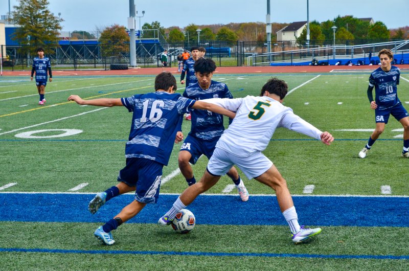 Sussex Academy sophomore Bodhi Williams battles with Saint Mark’s junior Justin Baxley along the sidelines as Ruendi Ortiz-Santos swoops in.