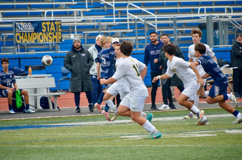 Sussex Academy senior Noah Benz flicks a ball as his classmate George Sapna runs toward it.
