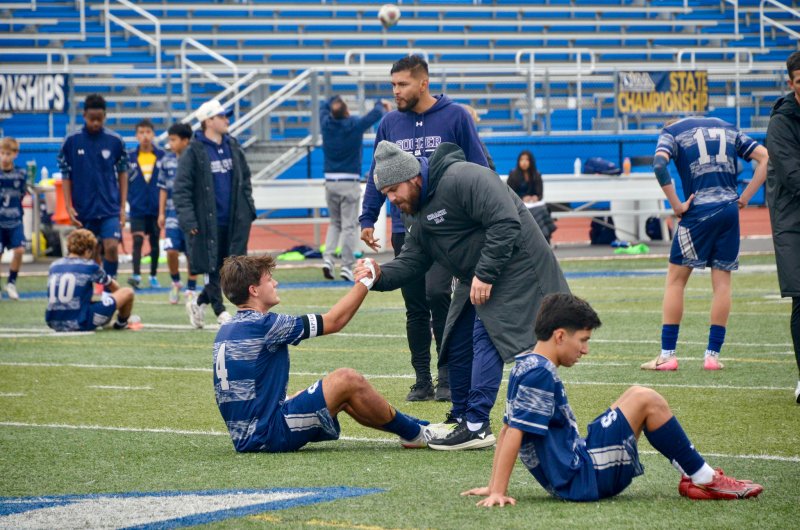 Sussex Academy head coach R.J. Dina lifts his captain Bent Steimel up off the pitch. Dina constantly praises Steimel’s leadership.