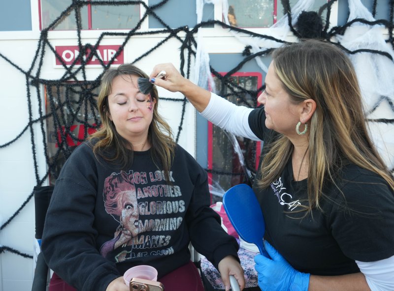 Nicole McConnell, left, sits as Catherine Flaherty paints her face.