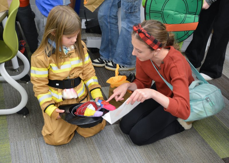 Mariner MS student Kinley Johnson shows Morgan Schneider of Milton Elementary School all the details on her monster.