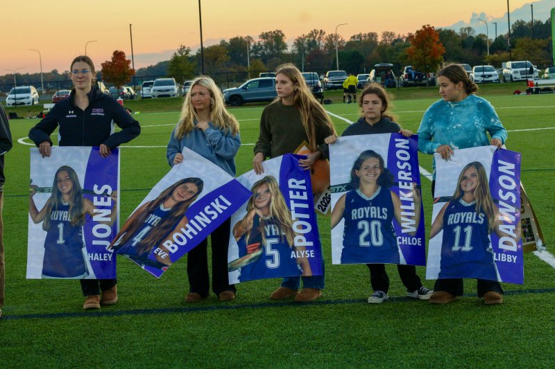 Underclassmen on the field hockey team play the role of poster holders.