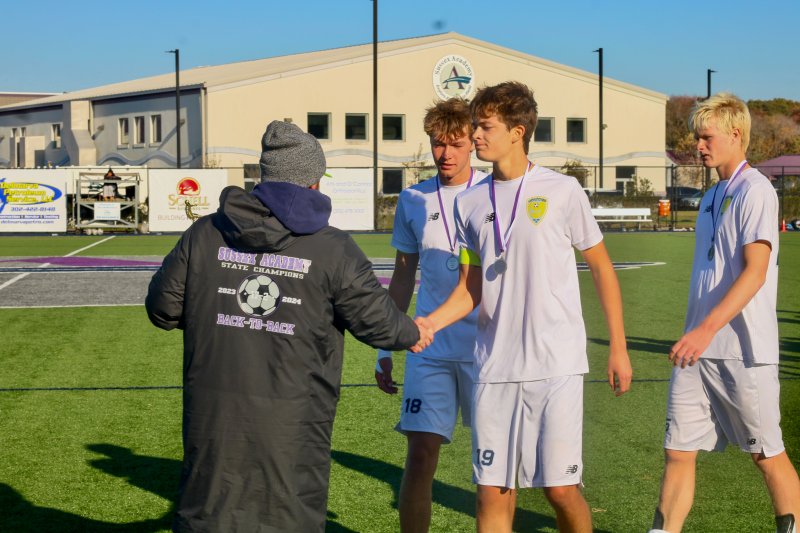 Cape senior Lee Levis shakes hands with Sussex Academy coach R.J. Dina as he, Lawson Whaley and Brenner Short accept their Henlopen North accolades.