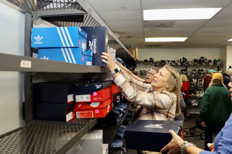 Dorian Gentzler sorts sneakers in the Clothing Our Kids warehouse. The shoes are all major brands, like Adidas, Reebok and Nike.