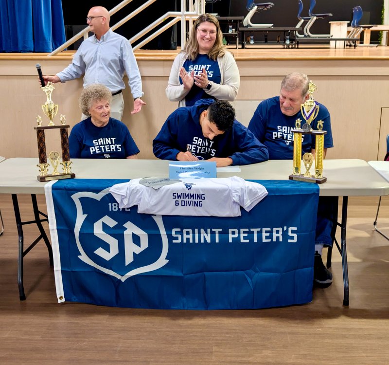As his swimming coach Tom Martiner prepares a speech in the background, Seahawks senior Christian Wright signs a letter of intent to swim at Saint Peter’s with his grandmother Mina and grandfather John at his side. His mom Kimberly cheers her son on in the back.
