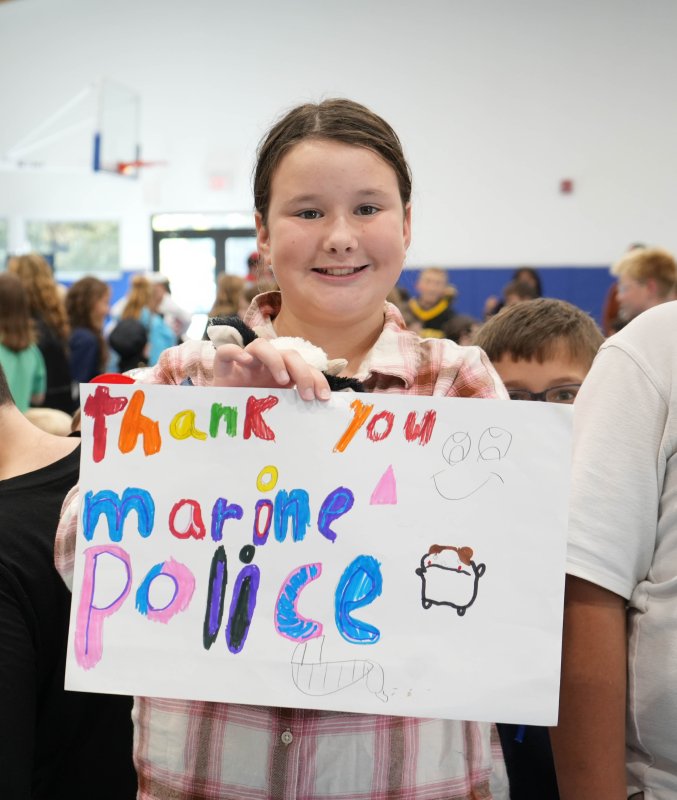 Fourth-grader Caroline Krajewski holds a sign thanking the marine police after the assembly.