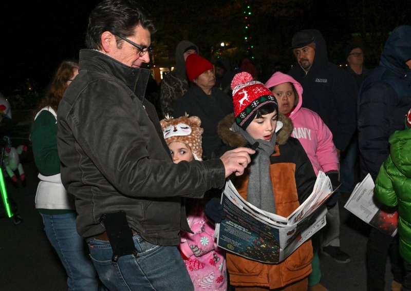 Michael Fink, right, sings carols as his father Shaun lights up the lyrics with his cellphone.