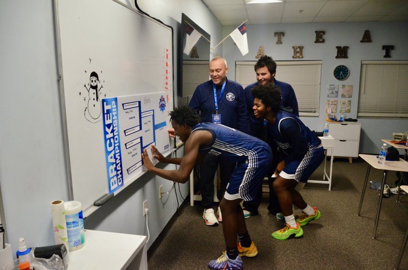 Sussex Academy sophomore Farmar Amisial puts the Sussex Academy sticker in the championship on the Salisbury Christian bracket board with Sebastian Paul watching after the Seahawks defeated Holly Grove 49-48 Dec. 29 in the Governor’s Challenge. AARON R. MUSHRUSH PHOTOS