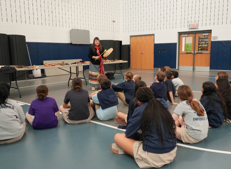 Boe Harris-Nakakakena plays a drum as students look on.