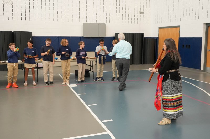 Sussex Academy sixth-graders experiment with various traditional musical instruments while Boe Harris-Nakakakena, far right, plays the Native American flute. The students are (l-r) Nash Dondarski, Kelly Samayoa-Gijalva, Jackson Sterner, Grant Hastings, Jace Hilderbrand, Adrian Andrews and Laurence Curry. Teacher Jon English stands in front of the students recording as they play the instruments.