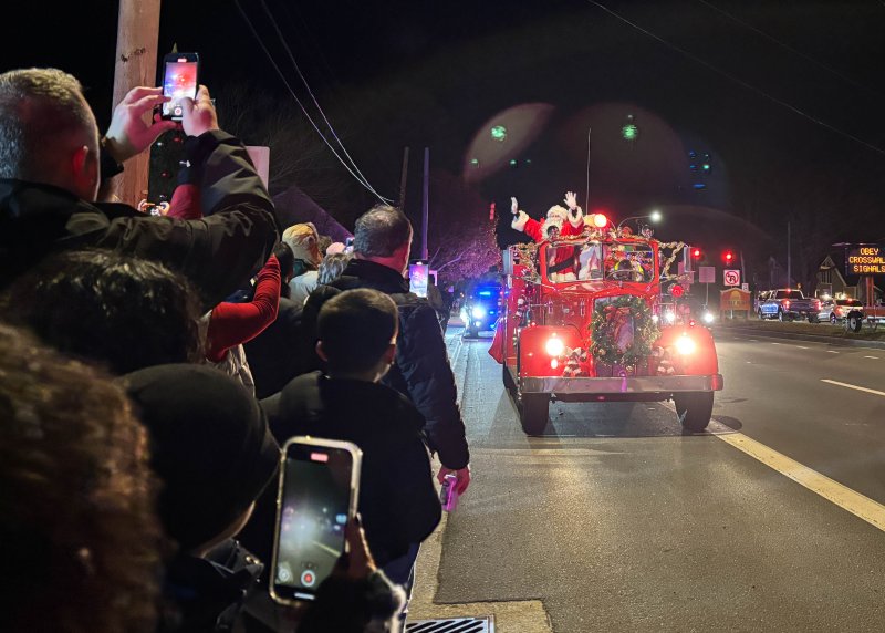 A crowd awaits Santa Claus, who waves from atop a fire truck, at Fifer’s Farm Kitchen Nov. 29.