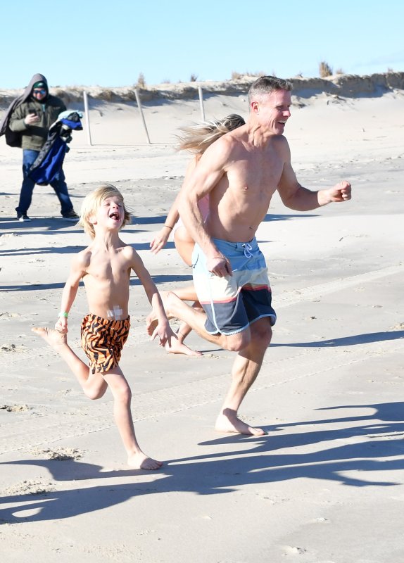 Polar Bear Bill Lingo, right, runs into the ocean with his son Cannon, 9.