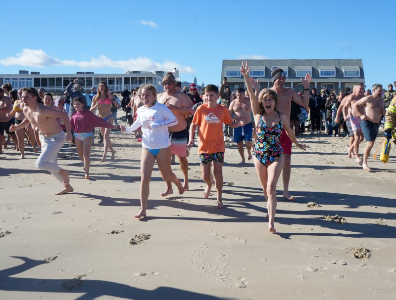 A group sprints toward the ocean for the 13th annual Dewey Dunk held New Year’s Day. ELLEN MCINTYRE PHOTOS