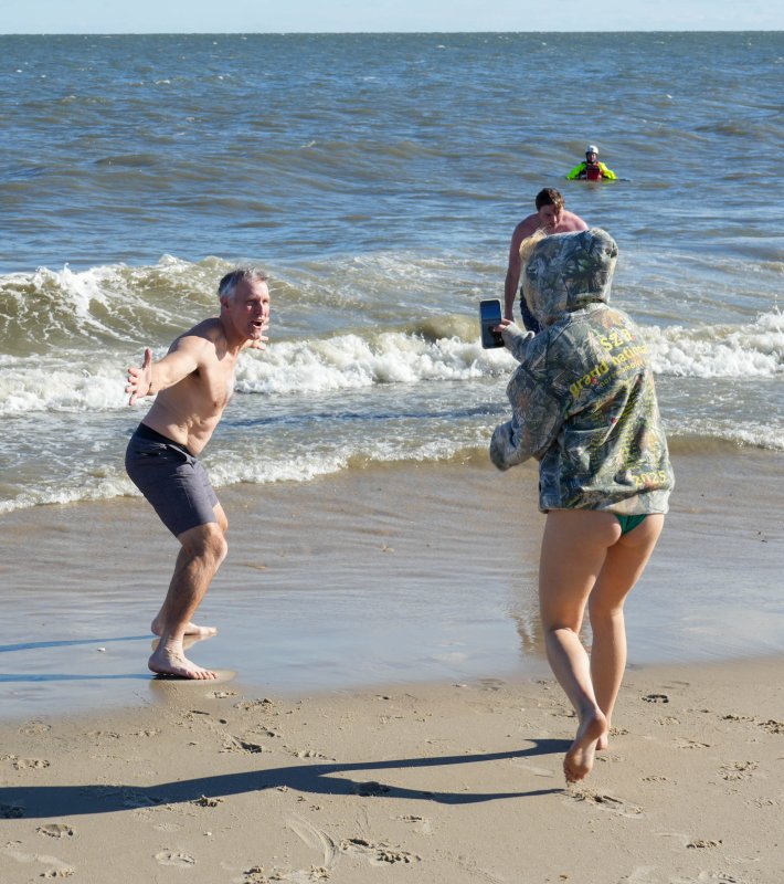 Darrell Helms, left, poses as his daughter, Remy, takes a picture of him running into the ocean.