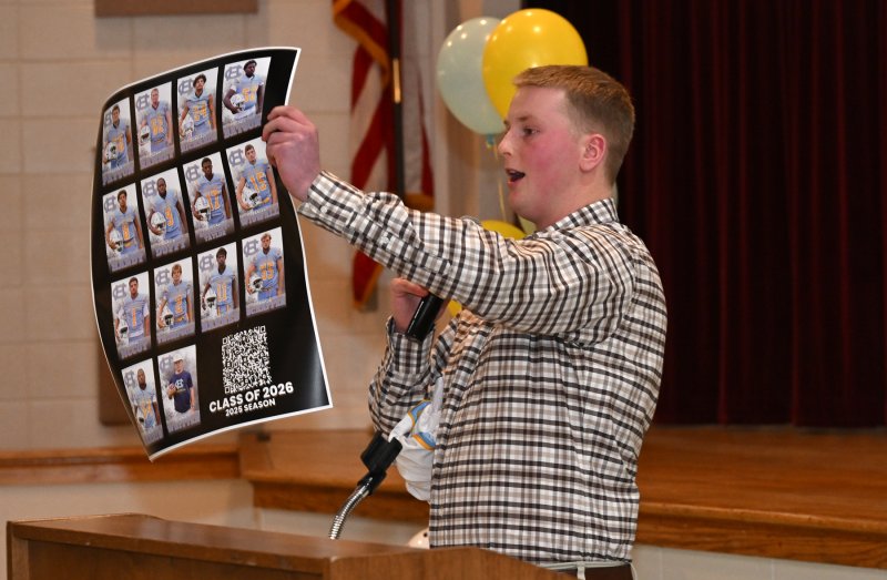 Senior Liam Ramsey presents the coaches with a poster of the seniors with a QR code to see pictures of the 2025 season.