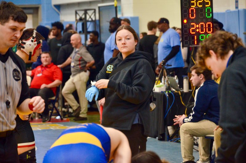 As she takes her glove off, Hollyann Wettstein looks over to see if her help is needed with the opponent of the wrestler she just took care of.