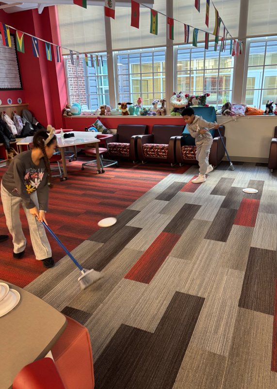 Trying out curling are students Quest Wilde Wilson, left, and Ayla Allen-Lopez.