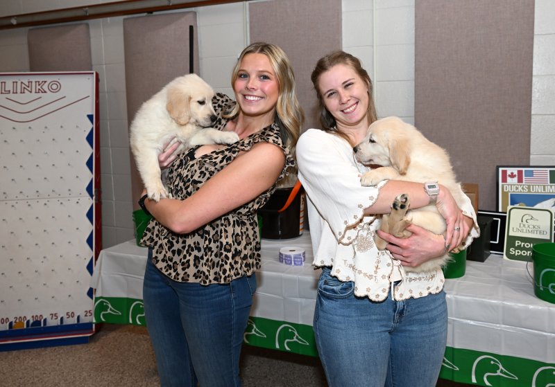 Jade Conaway and Julie Heffernan show some love to the two puppies up for the live auction.