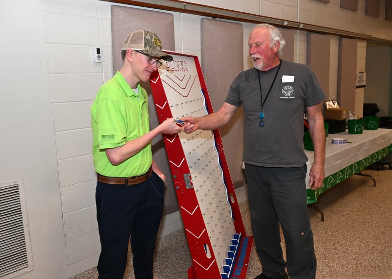 Rehoboth Beach firefighter Zach Simpler, left, assists Bob Lawrence with the Plinko game.