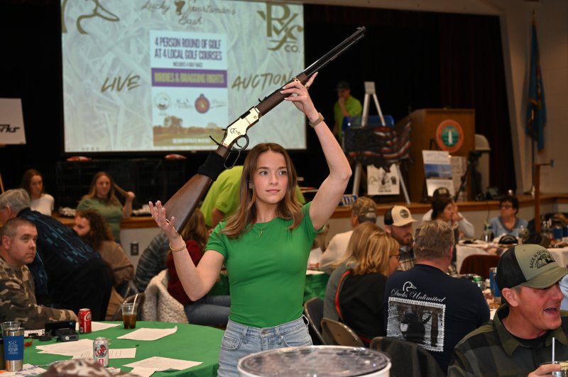 Ashley Lyons displays the Gunbash Custom Henry Golden Boy .22 long rifle up for live auction.