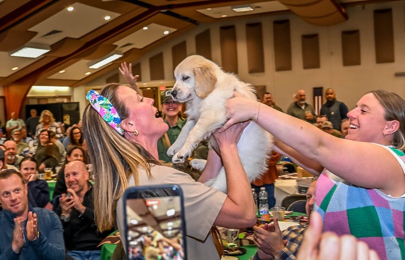 Volunteer Lynsy Oronzio delivers the golden retriever to the highest bidder, Meredith Hoffman.