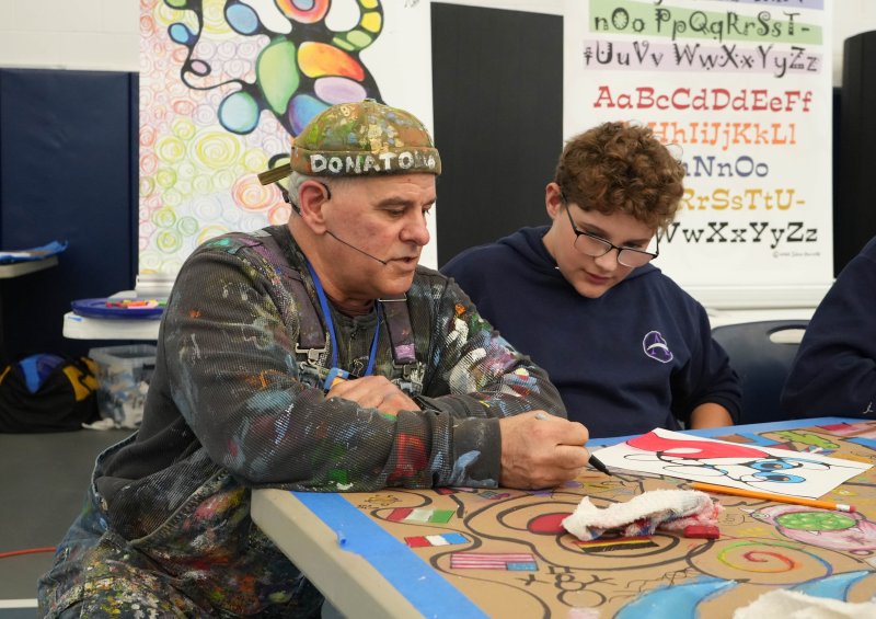 John Donato, left, known to students as Mr. Messy, helps eighth-grader Jordan Nicholls find some inspiration in his work.
