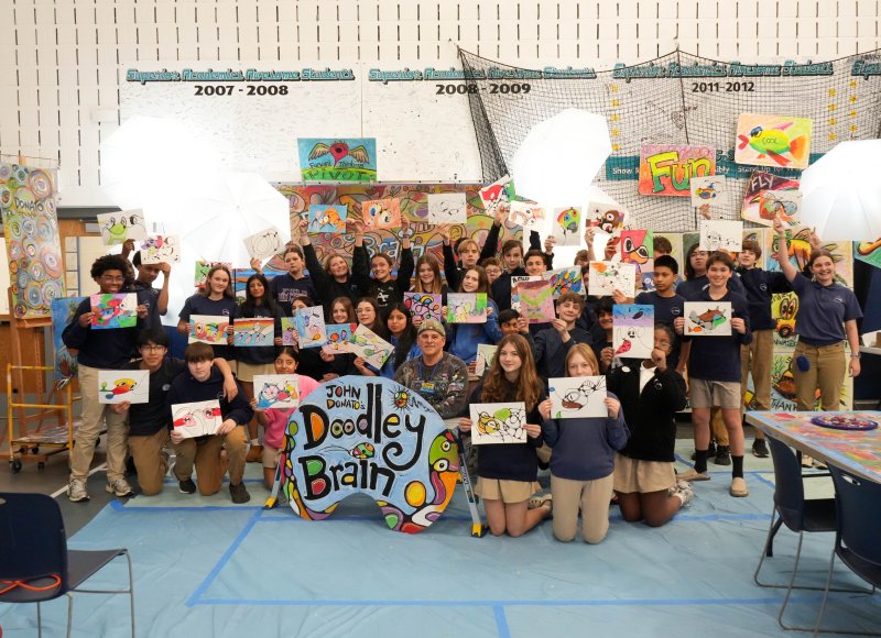 John Donato has the eighth-grade students hold up their finished art pieces.