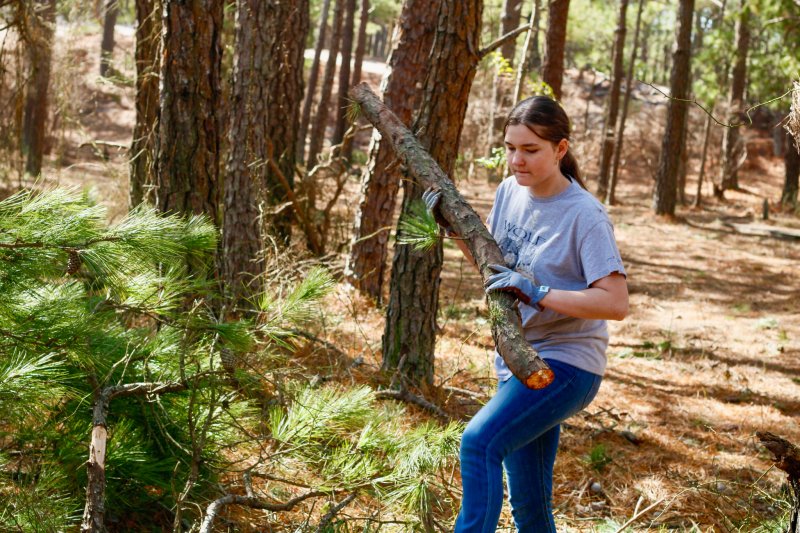 Curlett Walsh carries a log over to the pile.