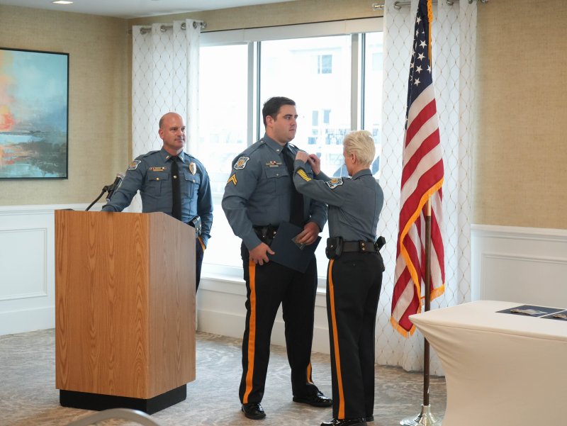 Chief Constance Speake, right, removes Staff Cpl. John Kane’s corporal badge to replace it with his new staff corporal badge. Lt. Cliff Dempsey looks on.