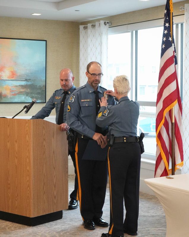 Master Cpl. Carl Kurten, middle, has his staff corporal badge removed by Chief Constance Speake to make room for his new master corporal badge. Lt. Cliff Dempsey stands left.