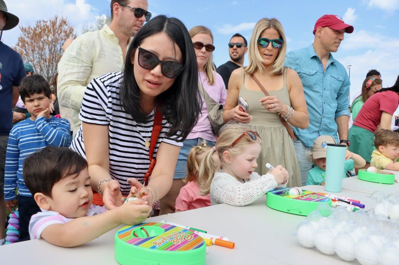 Noah Parente, left, gets some help from his mom at the Easter egg painting table.