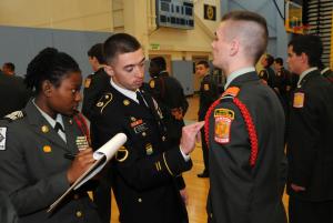 Cape Henlopen JROTC Cadet Cal Ballentine, right, is questioned about the placement of his ribbons by Staff Sgt. Dante Steel while JROTC cadet Sgt. Maj. Adonai Paraison, left, records evaluation notes during the accreditation inspection at Cape Henlopen High School. BY DAN COOK