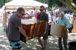 Tom Abbenante, left, and Brian Rybicki of Washington, D.C., help carry out a purchased antique hope chest for a friend while Frank Jacobs of Lewes follows with a similar find.