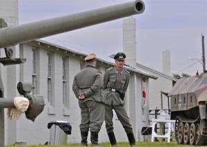 Re-enactors portraying German soldiers Bill Curtis, left, and Godfrey Althans watch a gun-firing drill. BY RON MACARTHUR