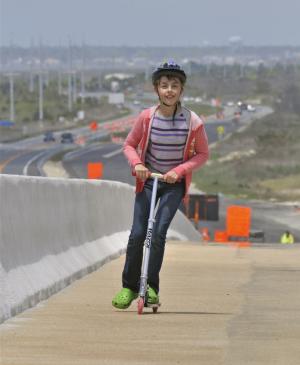 Gabby Guy, 11, who lives near Laurel, rides her scooter across the bridge span. BY RON MACARTHUR