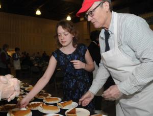 Brianna Johnson, left, chooses one of the many deserts on the table while volunteer Dee Speck keeps the table full. BY STEVEN BILLUPS
