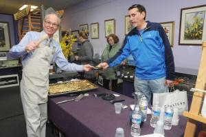 At the front of a long line at Tideline Gallery is Alan Gilbert of Ocean View as he takes a sample of a triple chocolate truffle tort from The Point Coffee House and Bake Shop Manager Tom Gross. BY STEVEN BILLUPS