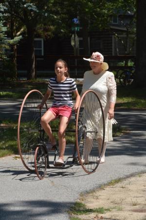 With Sue Lee keeping a watchful eye, Marissa Washburn of Greenville takes a ride on an antique three-wheel bike. BY RON MACARTHUR