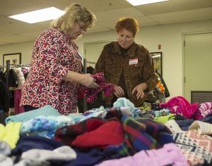 Volunteers Carla Wise, left, and Brenda Keith set up the accessory table during the coat ministry; 440 coats were donated. BY DENY HOWETH