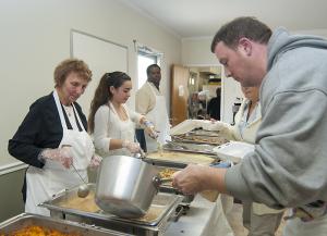 Mary Anne Alkrie, left, keeps a watchful eye on Todd Anderson who stopped in to volunteer and is put to work filling the gravy pan, while further down the line Alicia Hernandez and Phil Winder fill plates with turkey. BY DENY HOWETH