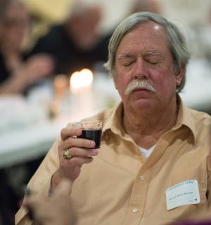 Deacon Marty Barrett from Mary Mother of Peace Catholic Church listens as one of the glasses of wine is prayed over. BY DENY HOWETH