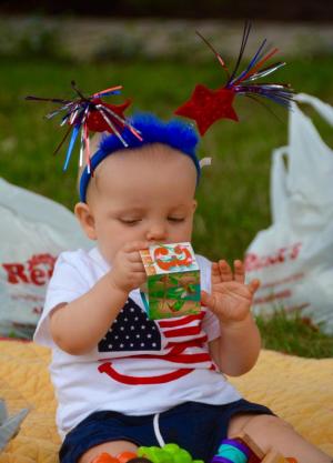 Eight-month-old Isaac Malin of Georgetown is more interested in a toy than watching the parade. RON MACARTHUR PHOTO