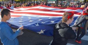 Students carry a large U.S. flag amid cheers from a large crowd around The Circle. RON MACARTHUR PHOTO