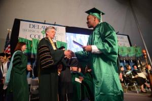 Aaron Felton from Rehoboth Beach makes his way across the stage with his communications degree diploma. Felton is shown shaking hands with Del Tech President Dr. Mark Brainard. Del Tech 2107